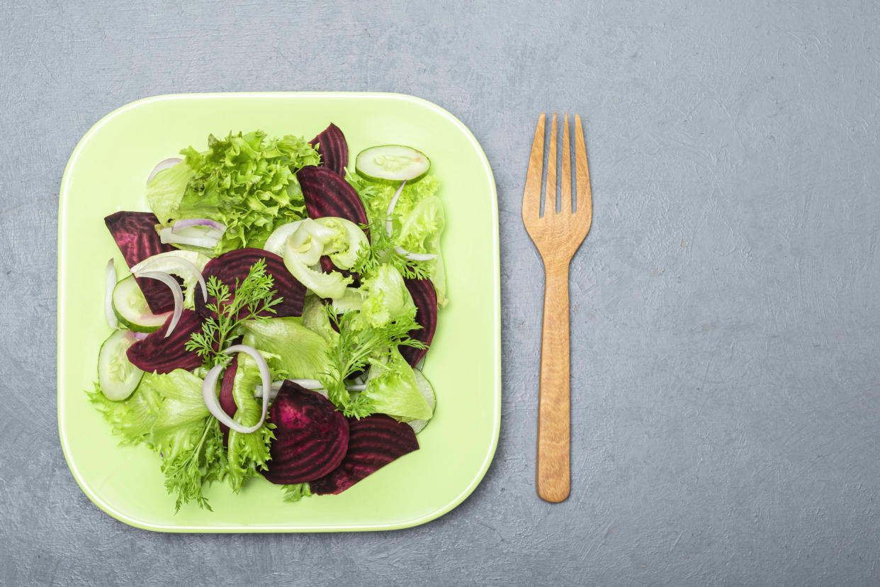 Beetroot salad in green bowl isolated on grey wood background close up, top view, healthy vegetable food concept.