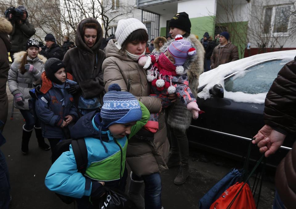 Women and children walk outside the premises of a high school, where a shooting incident has occurred, on the outskirts of Moscow, February 3, 2014. A Moscow high-school student shot a teacher and a police officer dead and held more than 20 other students hostage in a classroom on Monday before he was disarmed and detained, police said, just days before Russia hosts the Winter Olympics. (REUTERS/Maxim Shemetov)