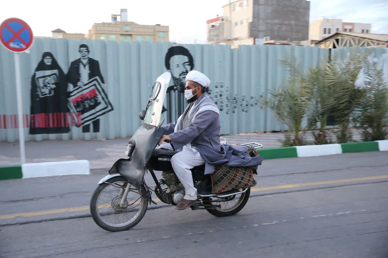 A cleric wearing a protective face mask, following the outbreak of coronavirus disease (COVID-19), rides his motorbike in Qom