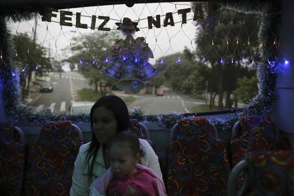 A mother with her daughter travel inside an urban bus decorated with Christmas motives while the bus driver Edilson (not pictured), 45, also known as "Fumassa", drives it in Santo Andre, outskirts of Sao Paulo December 10, 2013. Fumassa dresses as Santa Claus every year while driving his bus. Picture taken December 10. REUTERS/Nacho Doce (BRAZIL - Tags: SOCIETY TRANSPORT)