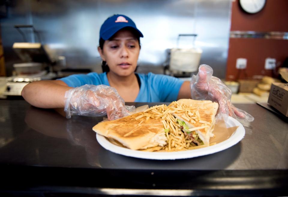 Jenny Jovel of Delicious Cuban Bakery serves a steak sandwich in the Marathon Station on  6710 Georgia Avenue.  (Meghan McCarthy  / The Palm Beach Post)