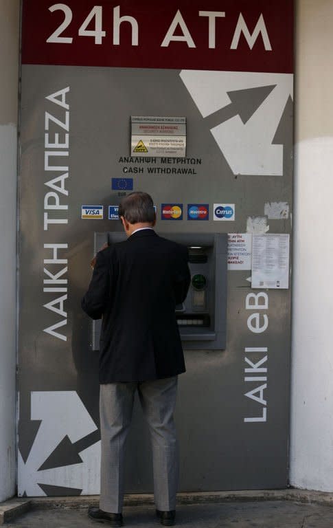 A man withdraws money from the ATM of a Laiki (Popular) Bank branch in central Nicosia on March 20, 2013. The finance ministry said banks, which last opened their doors on Friday, will remain closed again on Thursday and Friday "on grounds of public interest in order to ensure financial stability."