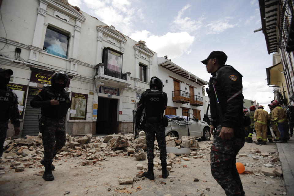 Police stand around building damaged after an earthquake struck Cuenca, Ecuador, Saturday, March 18, 2023. The U.S. Geological Survey reported an earthquake with a magnitude of 6.7 about 50 miles south of Guayaquil. (AP Photo/Xavier Caivinagua)