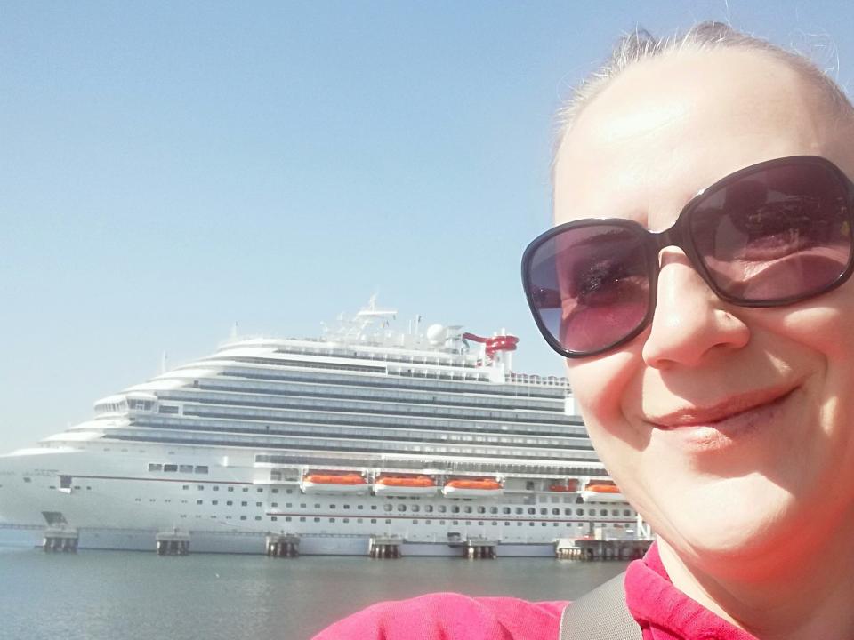 A woman taking a selfie in front of a cruise ship.