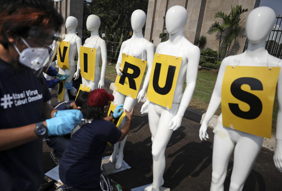 Greenpeace activists attach posters on mannequins displayed during a protest outside the parliament, amid the new coronavirus outbreak in Jakarta, Indonesia, Monday, June 29, 2020. About a dozen of activists staged the protest against the government's omnibus bill on job creation, saying that it undermined labor rights and environmental protection, and called on the parliament members to focus their attentions on efforts to contain COVID-19 outbreak instead. (AP Photo/Dita Alangkara)