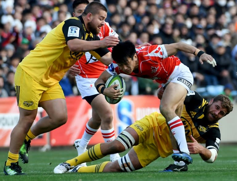 Sunwolves' Takaaki Nakazuru runs with the ball past Hurricanes' Dane Coles (L) and Callum Gibbins during their Super Rugby match, at the Prince Chichibu Memorial stadium in Tokyo, on February 25, 2017