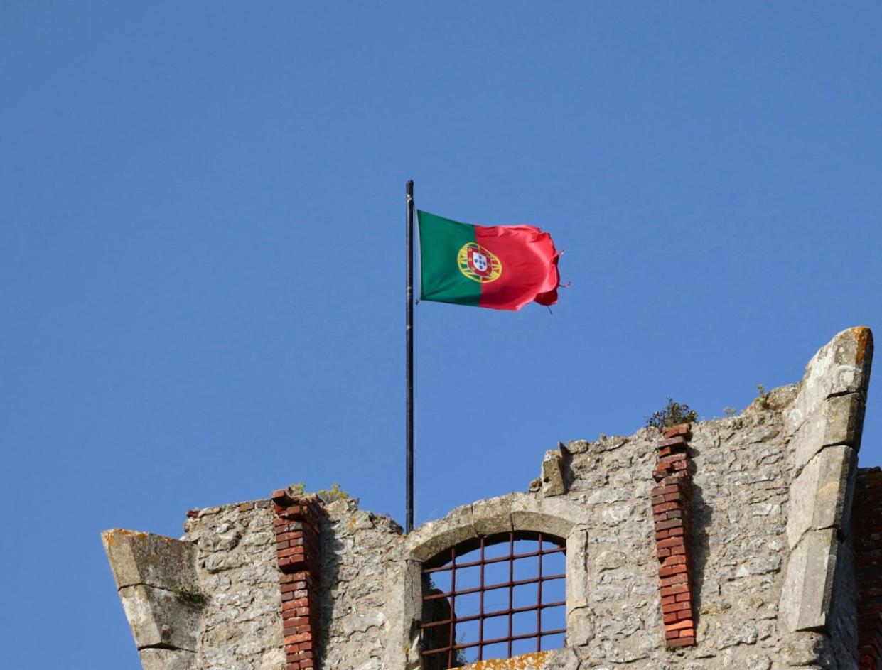 The flag of Portugal on ancient ruins.