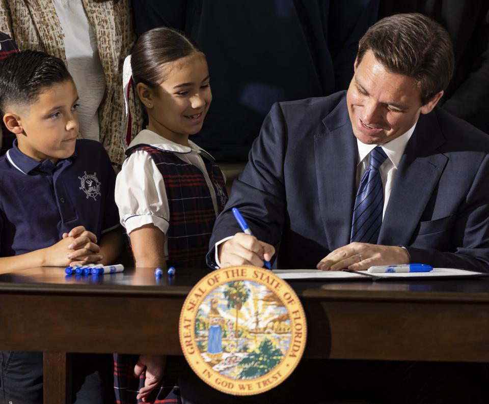 Florida Governor Ron DeSantis signs a bill to expand school vouchers across Florida during a press conference at Christopher Columbus High School on Monday, March 27, 2023, in Miami, Fla.(Matias J. Ocner/Miami Herald via AP)