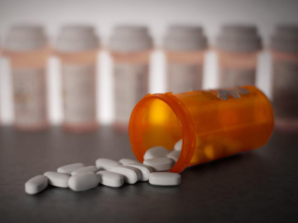 A staged photo showing pills spilling out of an orange bottle.