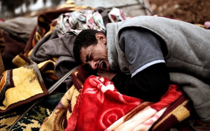 Relatives mourn as bodies of Iraqi residents of west Mosul killed in an airstrike targeting Islamic State  jihadists are placed and covered with blankets on carts on March 17, 2017.  - Credit: Getty