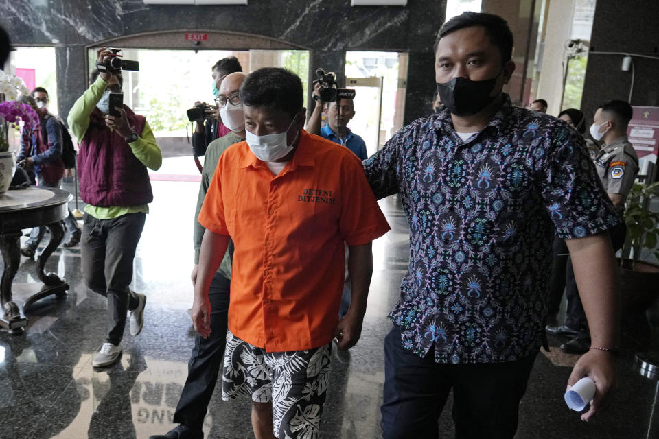 Immigration officers escort Mitsuhiro Taniguchi, 47, of Japan, center, before a press conference at immigration office in Jakarta, Indonesia Wednesday, June 8, 2022. Authorities on the southern tip of Indonesia's Sumatra island arrested a Japanese fugitive accused of fraud in Japan in connection with the receipt of a massive amount of COVID-19 subsidies for small businesses in distress, police said Wednesday.(AP Photo/Achmad Ibrahim)