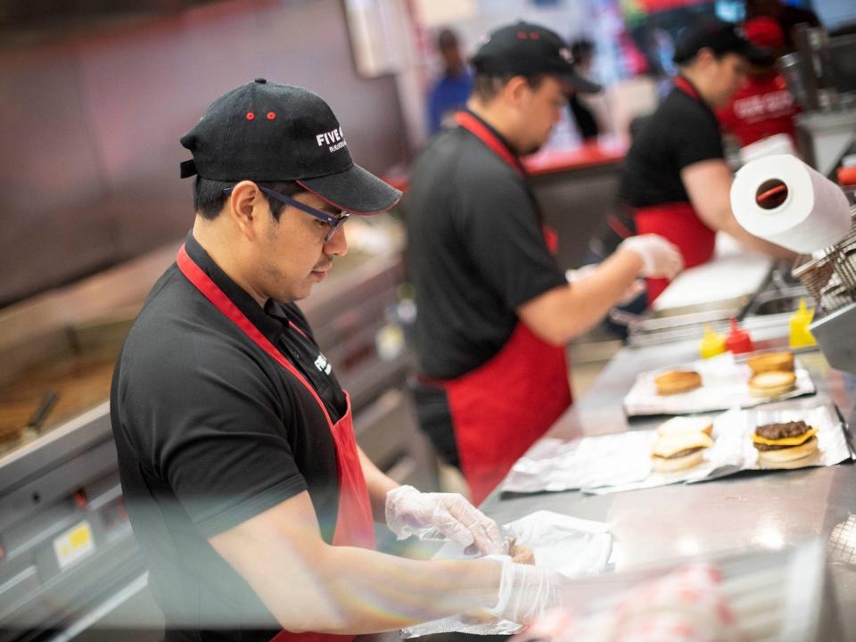 Workers prepare burgers at Five Guys in Kensington, London