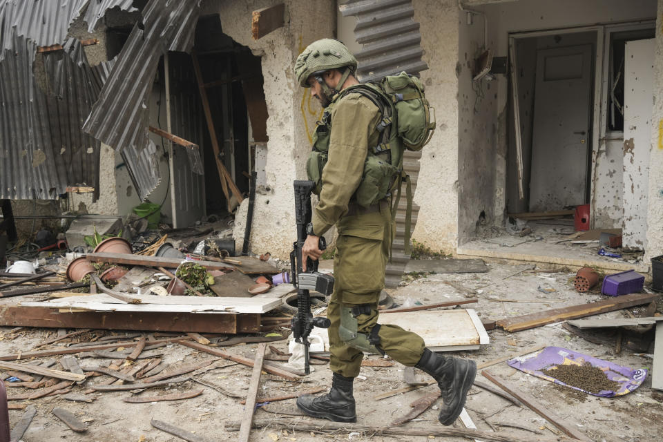 An Israeli soldier walks past a house damaged during the Hamas attack in Kibbutz Kfar Azza, Israel, Friday, Oct. 27, 2023. The Kibbutz was attacked on Oct. 7. (AP Photo/Maya Alleruzzo)