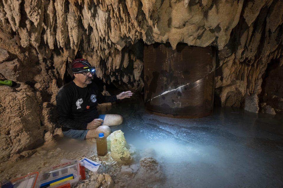 Engineer Guillermo D. Christy collects water samples while sitting next to a steel pillar filled with concrete, installed to support a part of the Maya Train track, inside the Aktun Tuyul cave system, on the outskirts of Playa del Carmen, Mexico, Sunday, March 3, 2024. Construction of the Maya Train is rapidly destroying much of the hidden underground world of caverns and sinkhole lakes, known as cenotes, already under threat by development and mass tourism. (AP Photo/Rodrigo Abd)