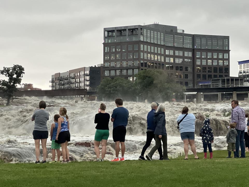 Visitors line up to get a glimpse of the waterfalls at Falls Park on Friday, June 21, 2024, in downtown Sioux Falls after torrential rain overnight.