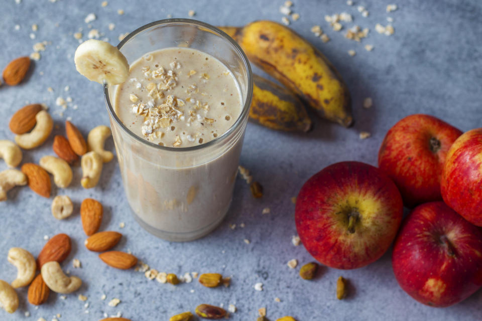 A photo of selective focus of healthy diet oats banana smoothie serve with dry fruits and nuts.