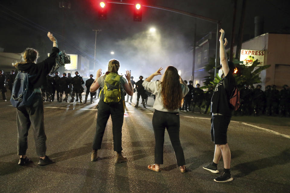 FILE - In this June 30, 2020, file photo, police stand in front of protesters gathered outside Portland Police Union headquarters in Portland, Ore. Thousands of protesters in the liberal and predominantly white city have taken to the streets peacefully every day for more than five weeks to decry police brutality, but recent violence by smaller groups is creating a deep schism in the protest movement and prompting allegations that white protesters are co-opting the moment. (Dave Killen/The Oregonian via AP, File)