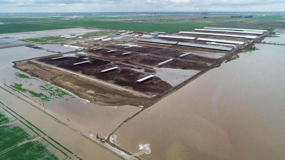 An excavator, bottom center, works to build a diversion berm to keep floodwater from a dairy in Kings County south of Hanford on Thursday, March 23, 2023.