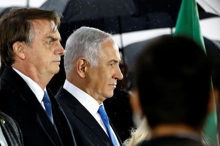 Brazilian President Jair Bolsonaro and Israeli Prime Minister Benjamin Netanyahu stand as it rains during a welcoming ceremony upon Bolsonaro's arrival in Israel, at Ben Gurion International airport in Lod, near Tel Aviv, Israel March 31, 2019. REUTERS/Ronen Zvulun