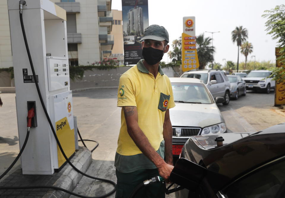 A gas station worker fills gasoline at a car, as other cars, background, line up amid fuel shortages, in Beirut, Lebanon, Wednesday, July 29, 2020. Lebanon is hurtling toward a tipping point at an alarming speed, driven by financial ruin, collapsing institutions, hyperinflation and rapidly rising poverty _ with a pandemic on top of that. The collapse threatens to break a nation seen as a model of diversity and resilience in the Arab world.(AP Photo/Hussein Malla)