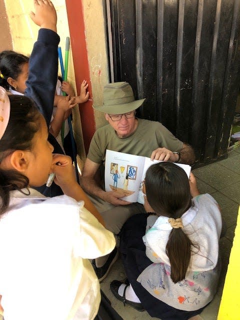 Chaplain Norris Burkes reads a book to children at a Honduran elementary school in 2020.