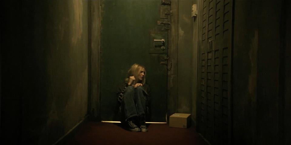 Sasha Luss in a dimly lit corridor, looking towards a door, expressing concern in Latency