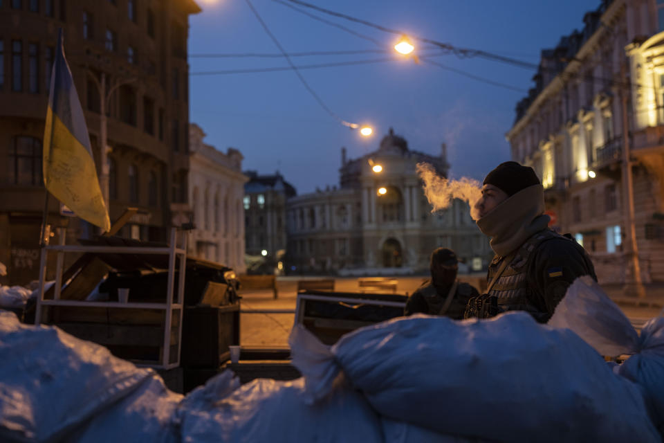 FILE - A Ukrainian soldier smokes as he and another soldier stand guard behind sandbags and in front of the National Academic Theatre of Opera and Ballet building, in Odesa, Ukraine, March 24, 2022. The Black Sea port is mining its beaches and rushing to defend itself from a Mariupol-style fate. Some Western officials believe the city, which is dear to Ukrainians' hearts, could be next. (AP Photo/Petros Giannakouris, File)