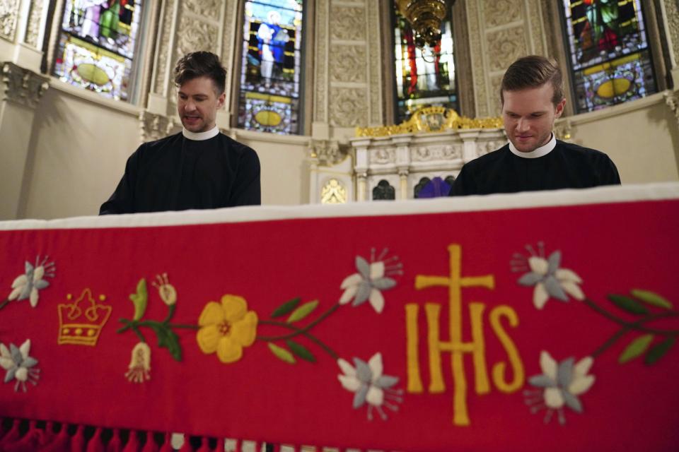 In this Sunday, March 29, 2020 photo, the Rev. Steven Paulikas, left, and curate Spencer Cantrell place a frontal on the altar for Palm Sunday, which will be commemorated virtually this year, at All Saints' Episcopal Church in the Brooklyn borough of New York. The global coronavirus pandemic is upending the season's major religious holidays, forcing leaders and practitioners across faiths to improvise. (AP Photo/Emily Leshner)
