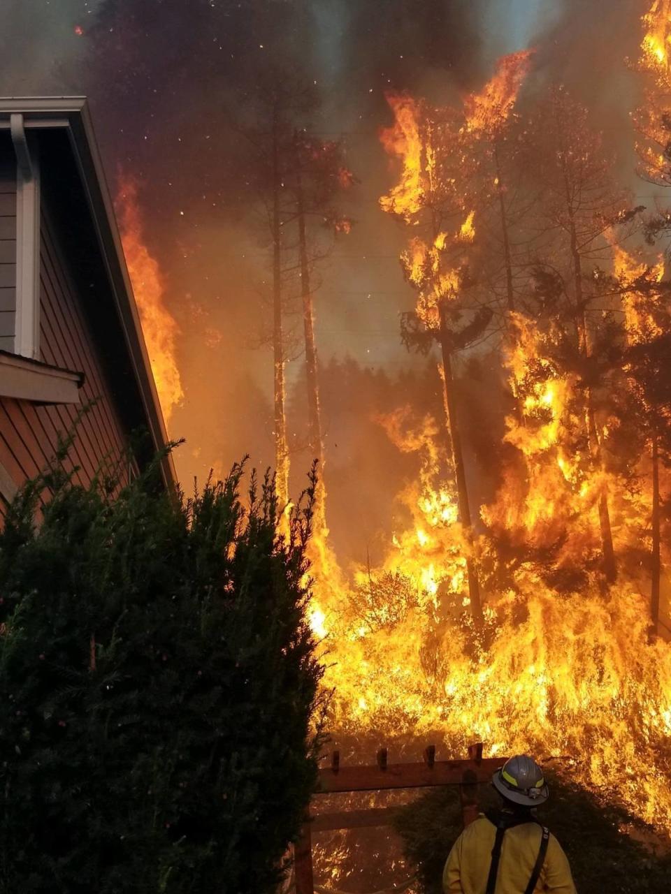 A firefighter stands in front of the Sumner Grade Fire blaze in September 2020.