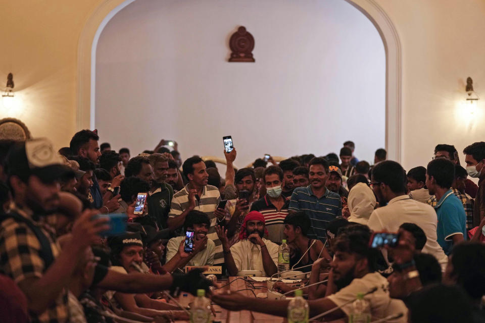 Protesters pretend to hold a cabinet meeting after occupying seats at the cabinet meeting hall of president's official residence a day after it was stormed in Colombo, Sri Lanka, Sunday, July 10, 2022. Sri Lanka’s president and prime minister agreed to resign Saturday after the country’s most chaotic day in months of political turmoil, with protesters storming both officials’ homes and setting fire to one of the buildings in a rage over the nation's severe economic crisis.(AP Photo/Eranga Jayawardena)
