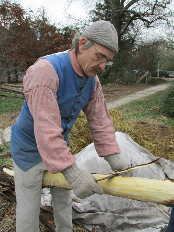 Colonial Williamsburg garden historian Wesley Greene strips the bark from a locust log with a draw knife. The log will be used as garden-bed edging in the town.