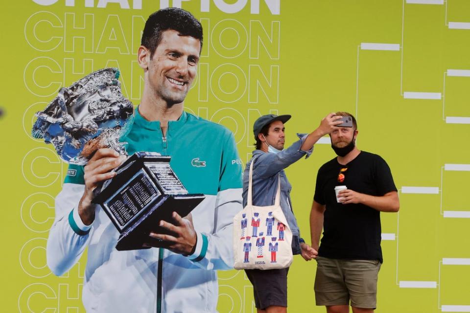 Fans take a photo in front of a picture of Novak Djokovic at Melbourne Park (Hamish Blair/AP) (AP)