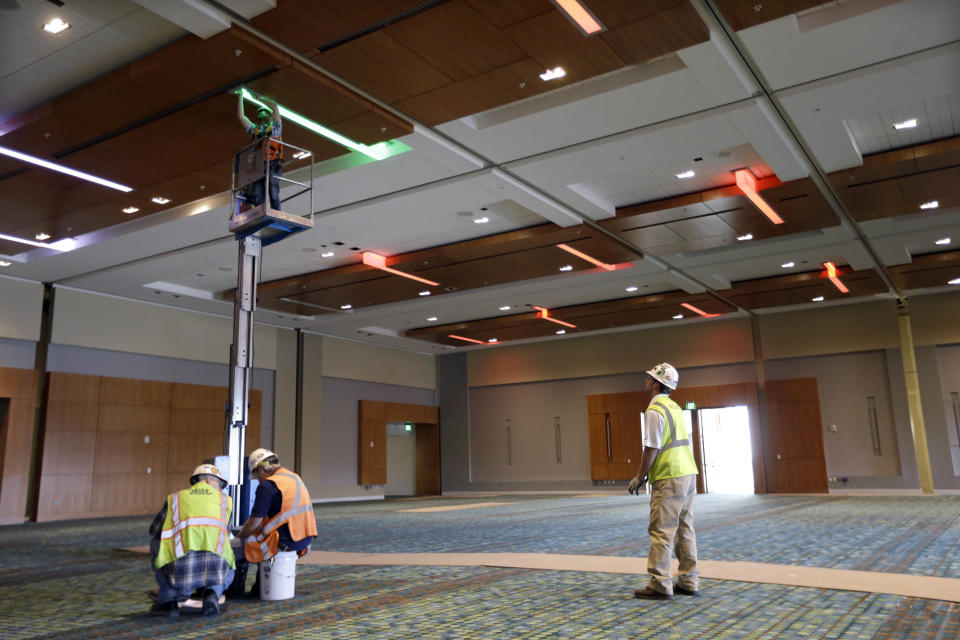 This April 12, 2013, photo shows workers installing colored lighting in the Music City Center in Nashville, Tenn. Nashville's new convention center is transforming the look of downtown with its wavy roof dominating six city blocks, but tourism officials hope the eye-catching facility will also show business travelers a revitalized Music City. (A P Photo/Mark Humphrey)