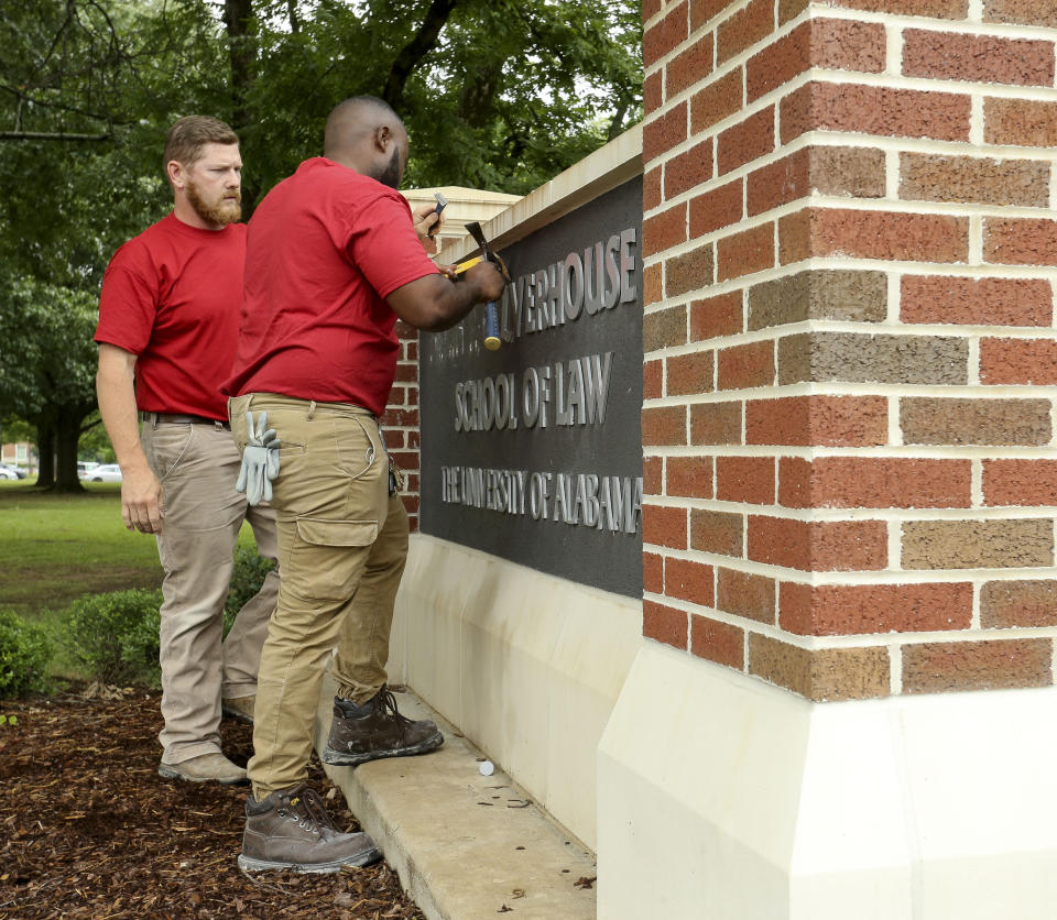 University of Alabama employees Joe Densmore, left, and Jeremy Scales remove the name of Hugh F. Culverhouse Jr. off the School of Law sign in Tuscaloosa, Ala., Friday, June 7, 2019. The University of Alabama board of trustees voted Friday to give back a $26.5 million donation to a philanthropist Hugh F. Culverhouse Jr., who recently called on students to boycott the school over the state's new abortion ban. (GaryCosby Jr./The Tuscaloosa News via AP)
