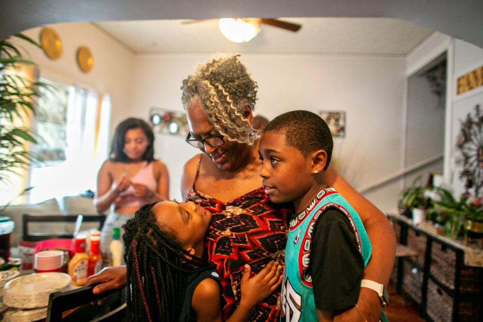 A woman hugs two children