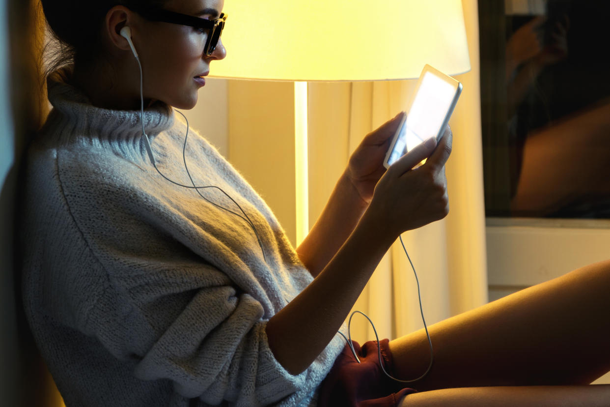 Young woman wearing a warm pullover is using tablet PC in the middle of the night in winter. (Getty Images)