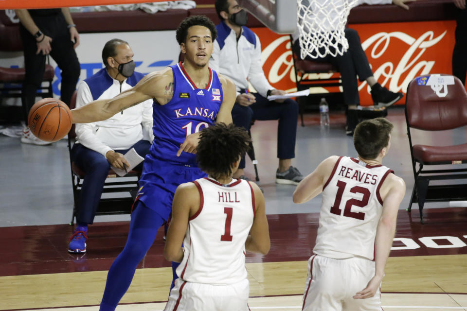 Kansas forward Jalen Wilson (10) throws the ball away from Oklahoma forward Jalen Hill (1) and guard Austin Reaves (12) during the second half of an NCAA college basketball game in Norman, Okla., Saturday, Jan. 23, 2021. (AP Photo/Garett Fisbeck)