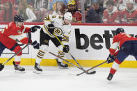 Boston Bruins center Pavel Zacha (18) passes the puck past Florida Panthers center Evan Rodrigues (17) and center Anton Lundell (15) during the second period of Game 1 of the second-round series of the Stanley Cup Playoffs, Monday, May 6, 2024, in Sunrise, Fla. (AP Photo/Wilfredo Lee)