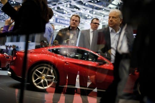 Visitors stand near a Ferrari model car reflected at the Italian car maker's booth at the Geneva Motor Show. Sports cars, reputed for being energy guzzlers, are now trying to boost their green credentials as they seek to attract environmentally conscious consumers and meet new climate standards