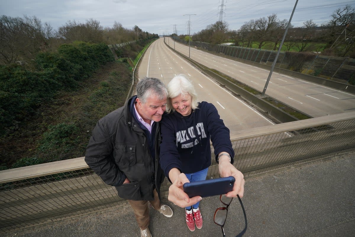 iona and Patrick Potter, residents of West Byfleet take a selfie on the Parvis Road bridge in Byfleet, that crosses over a closed section of the M25 between Junctions 10 and 11, while a bridge is demolished and a new gantry is installed. (Yui Mok/PA Wire)