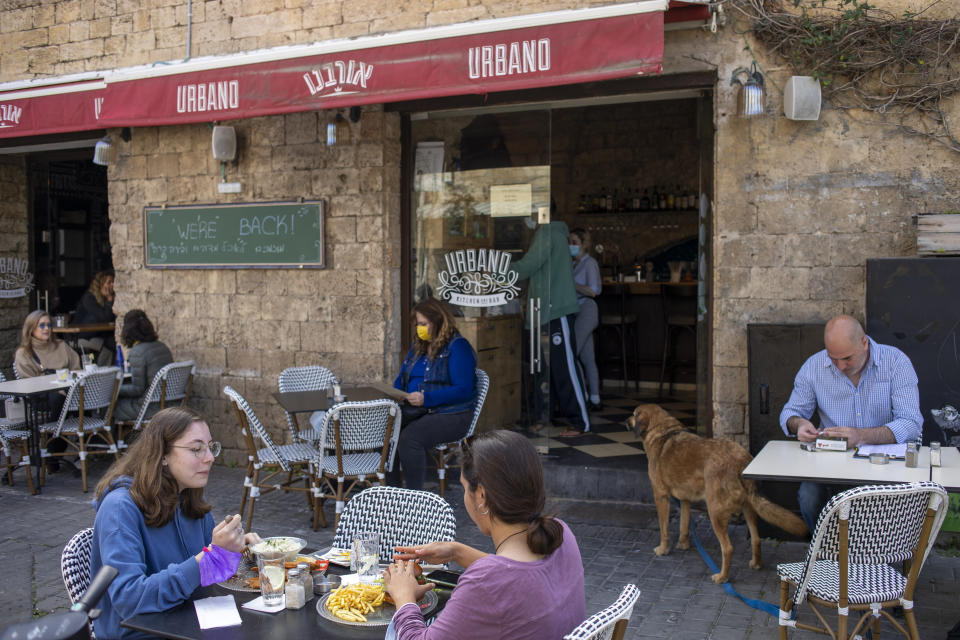 FILE - In this March 7, 2021, file photo, people eat in a restaurant as restrictions are eased following months of government-imposed shutdowns, in Tel Aviv, Israel. While Israel provides a glimpse of what may be possible with high immunization rates, it also offers insight into the problems that lie ahead: Workplaces and schools are now grappling with what to do with those who refuse to get vaccinated. (AP Photo/Ariel Schalit, File)