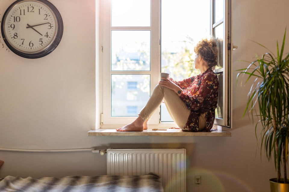 Beautiful young woman sitting at a window sill having rest