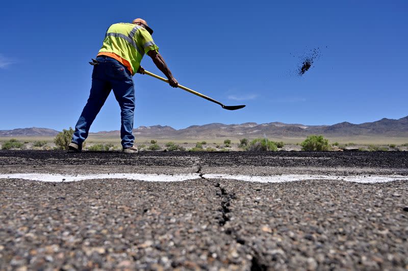 FILE PHOTO: A crack across the roadway is seen as Nevada Department of Transportation worker Jarrid Summerfelt repairs damage to U.S. Highway 95 after a strong earthquake struck near Tonopah