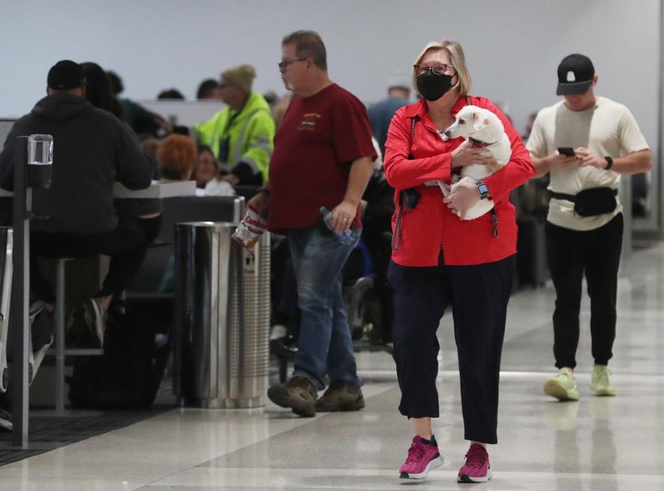 Liz Elden carries her dog Gilligan as she waits for her flight to depart at the Akron-Canton Airport in Green on Thursday. Lisa Dalpiaz, airport spokeswoman, said airport crews are prepared to keep the runways clear for flights. However, she said passengers should check with airlines before they come to the airport for any delays or cancellations.