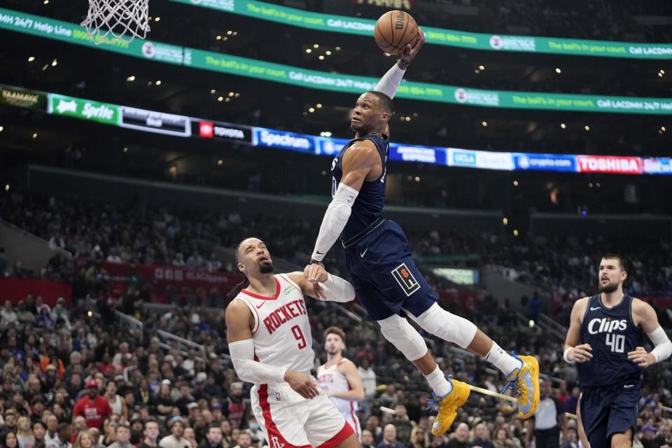 Clippers guard Russell Westbrook attempts a dunk after hitting Rocket Dillon Brooks in the face as Ivica Zubac watches