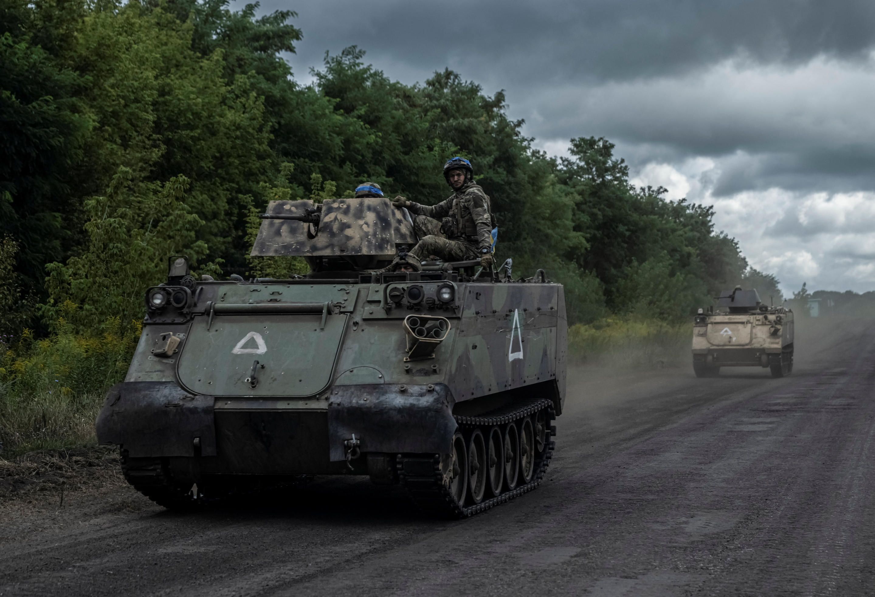 Ukrainian servicemen ride armored personnel carriers.