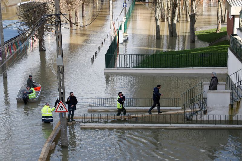 Municipal employees assists residents who walk on elevated boards as the Marne River overflows its banks in Gournay-sur-Marne, near Paris