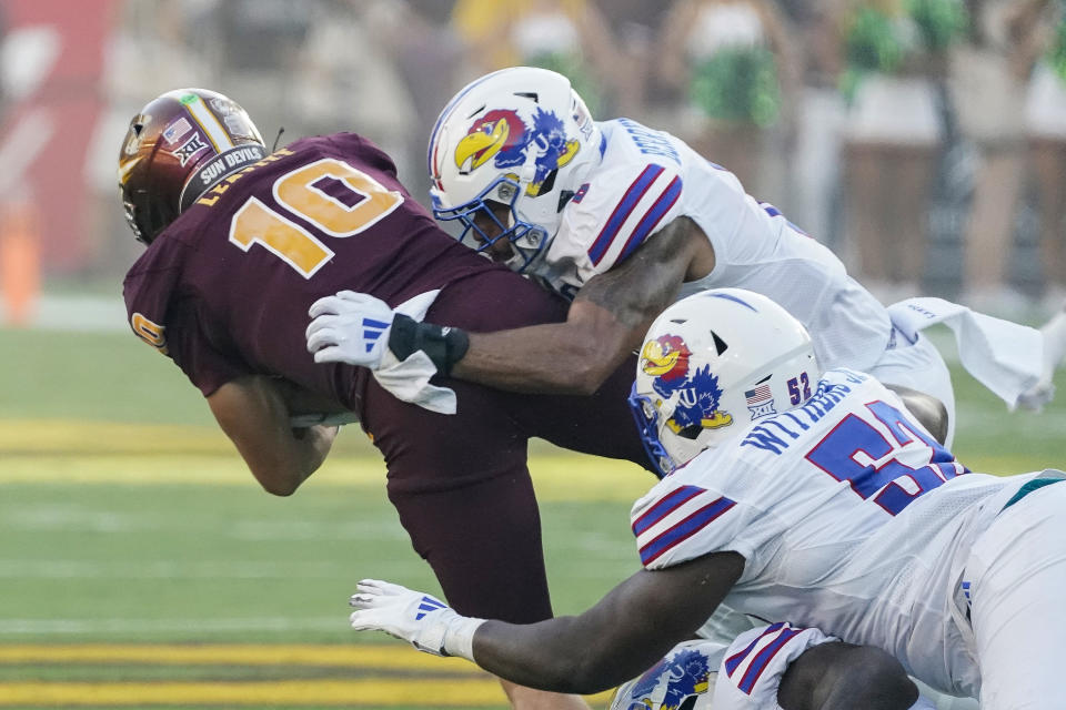 Kansas linebacker Taiwan Berryhill Jr., right, and defensive tackle D.J. Withers, lower right, bring down Arizona State quarterback Sam Leavitt (10) during the first half of an NCAA college football game Saturday, Oct. 5, 2024, in Tempe, Ariz. (AP Photo/Darryl Webb)