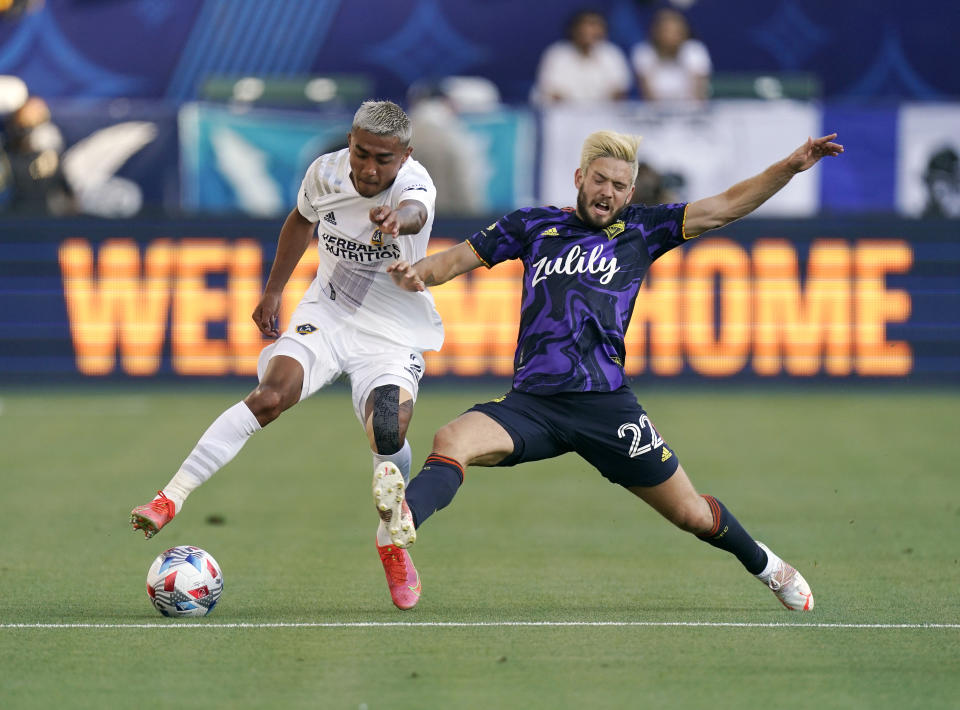 LA Galaxy defender Julian Araujo, left, battles for the ball with Seattle Sounders midfielder Kelyn Rowe during the first half of a Major League Soccer match Saturday, June 19, 2021, in Carson, Calif. (AP Photo/Mark J. Terrill)