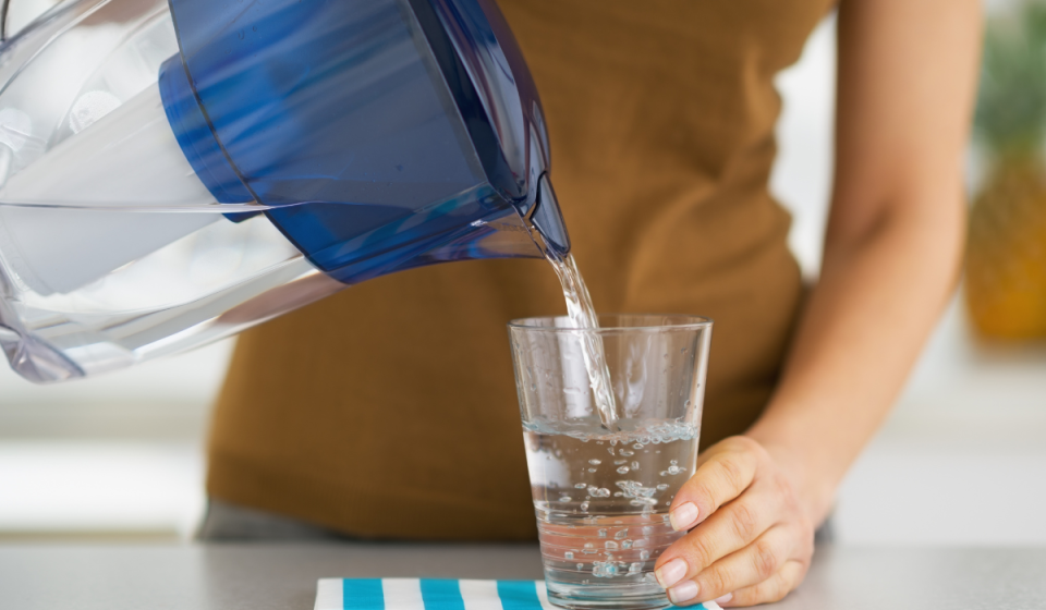 someone pouring water from a pitcher into a glass